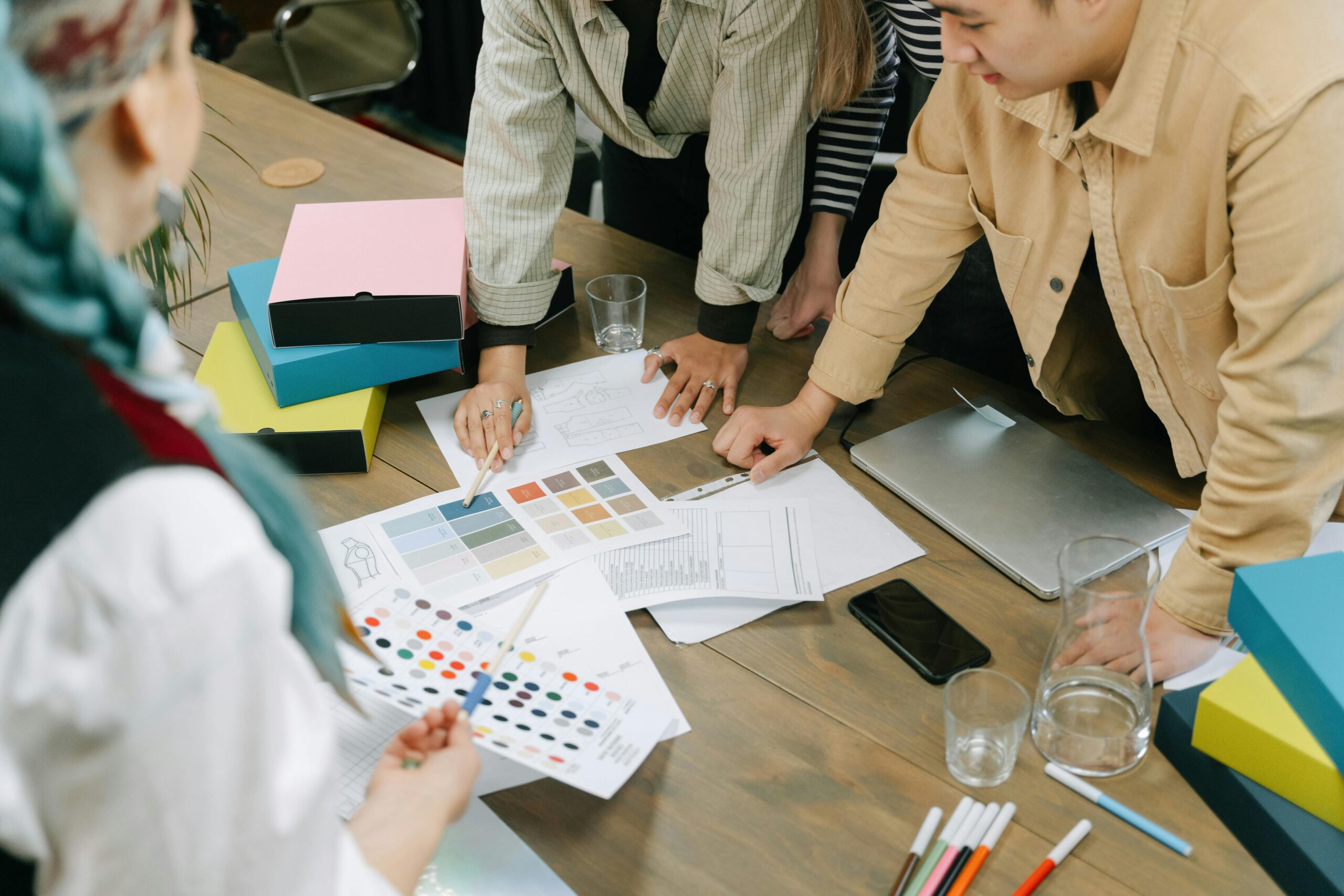 Creative professionals engaged in a design meeting, sharing ideas and color schemes.